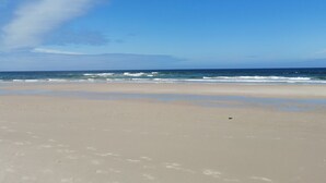 Een strand met een heldere lucht en een rustige zee.