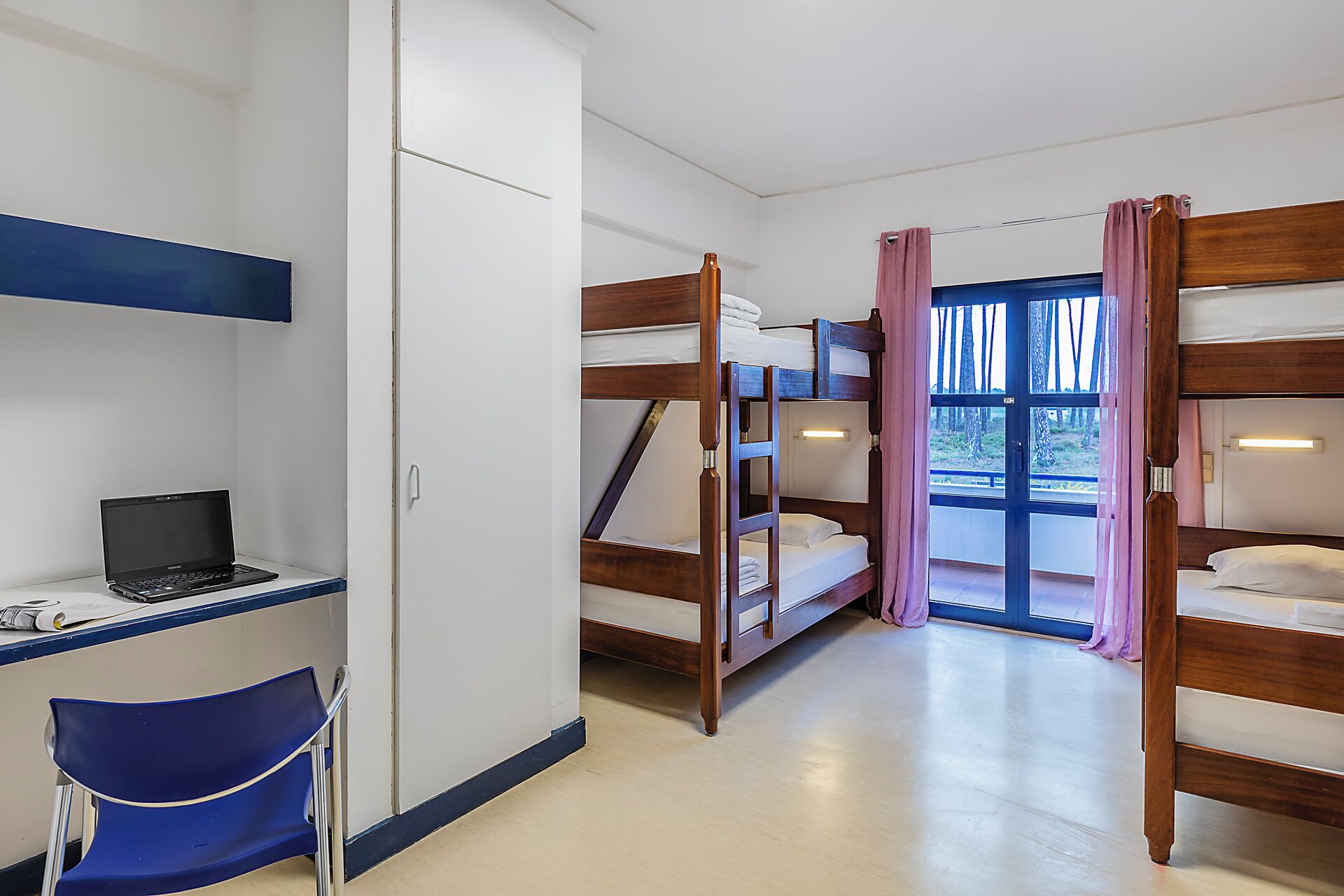 Une chambre avec des lits superposés, un bureau avec un ordinateur portable et une chaise.
