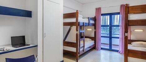 A room with bunk beds, a desk with a laptop, and a chair.