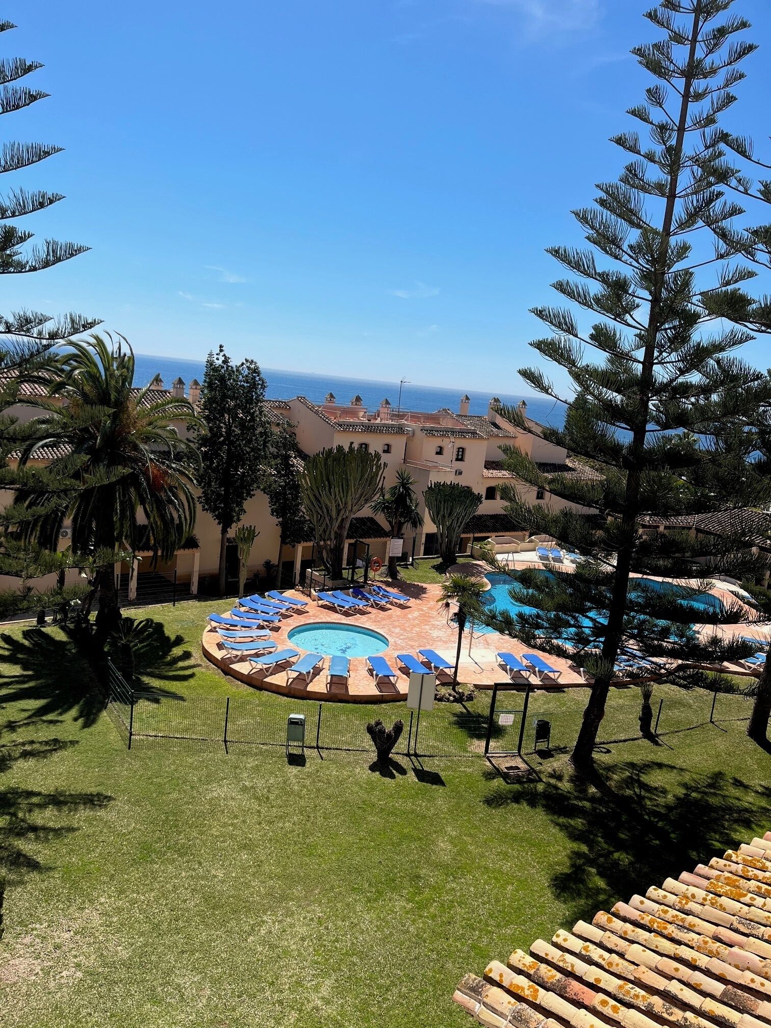 Un resort con zona de piscina, palmeras y vista al mar.