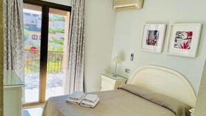 A hotel room with a bed, a nightstand, a lamp, and a view of the outside balcony. - Apartamentos El Toro (Marbella)