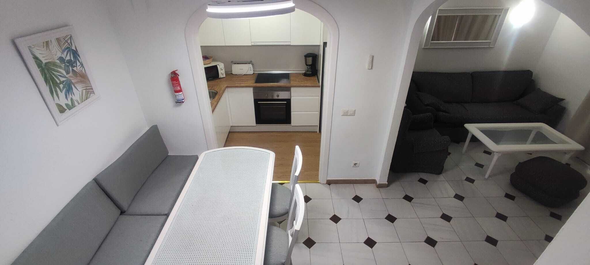 Un espacio habitable compacto con kitchenette, comedor y zona de estar.