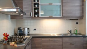Una cocina moderna con estufa a gas, cafetera y una estantería empotrada con plantas en macetas.