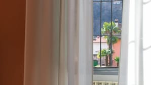 Una habitación con cama, una silla y una ventana con cortinas.