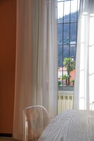 Ein Zimmer mit einem Bett, einem Sessel und einem Fenster mit Vorhängen.