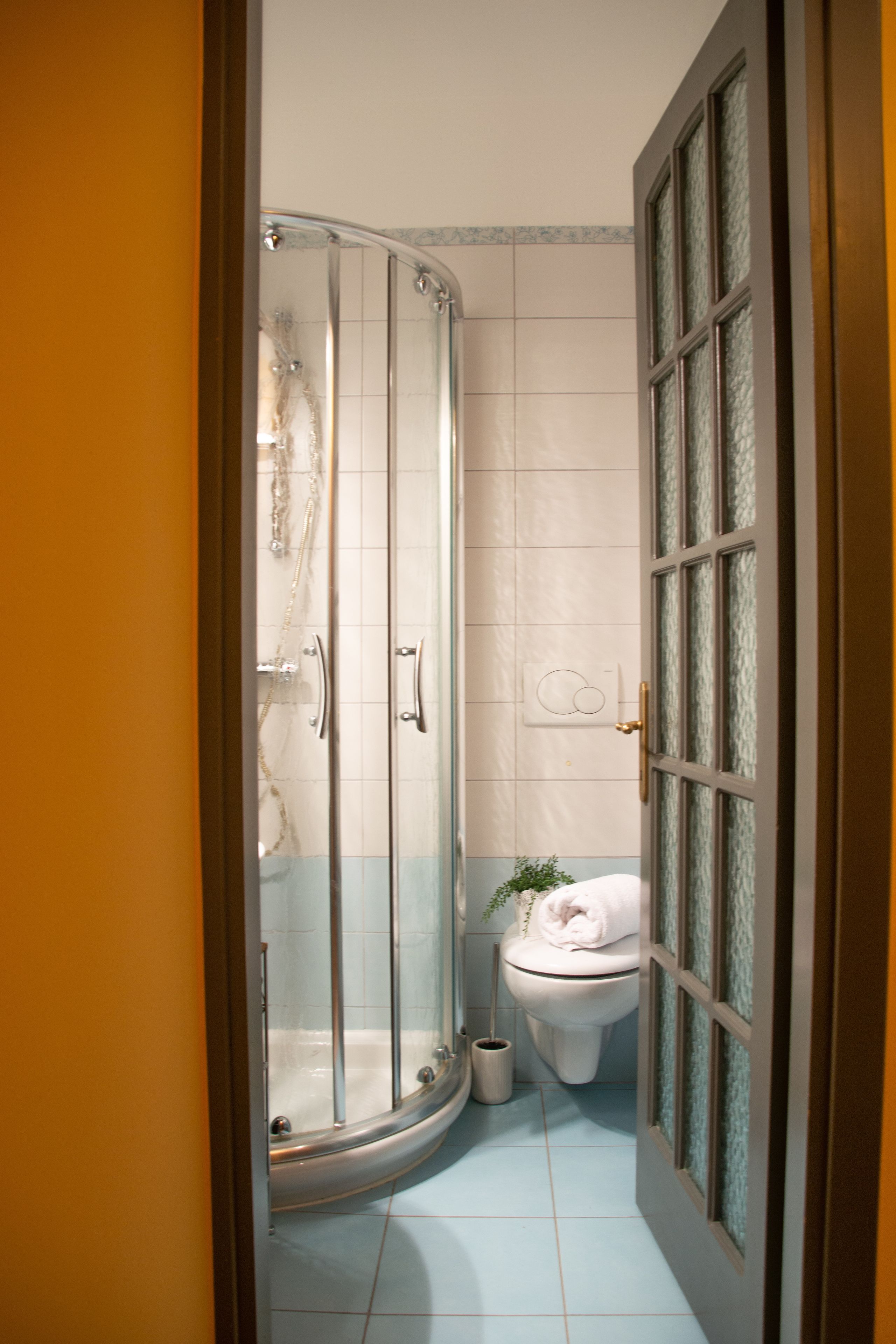 A bathroom with a glass-enclosed shower, a toilet, and a sink.