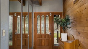 A wooden door with glass panels and a potted plant beside it.