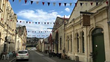 A street lined with historic buildings, a car parked on the side, and a clear sky with clouds.