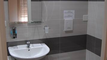 Un baño con lavamanos blanco, inodoro y espejo.