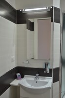 Un baño con lavamanos blanco, un espejo y dispensador de toallas.
