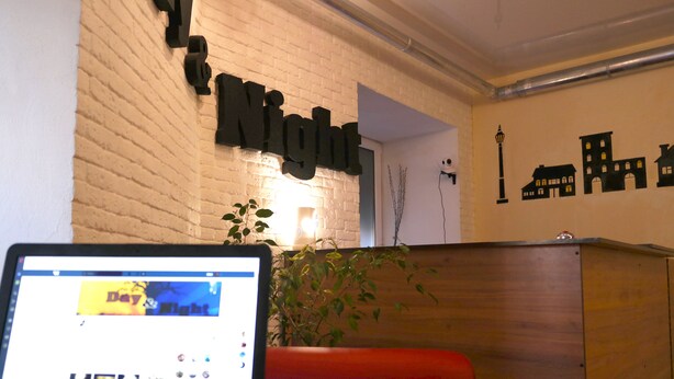 A reception desk with a laptop, a brick wall, and a sign that reads "Night." - Day & Night - Hostel (Odesa)