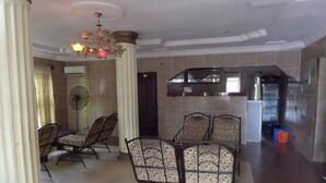 A dining area with patterned chairs, a chandelier, and a kitchen in the background. - Fatty K Hotel and Suites (Ota)