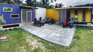 A courtyard with a paved area, two small buildings, and several parked scooters. - Lumut Cube Homestay Kontena (Lumut)