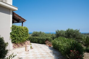 Stroll along the paved pathway to a serene seating area, surrounded by lush greenery and offering a peaceful retreat.