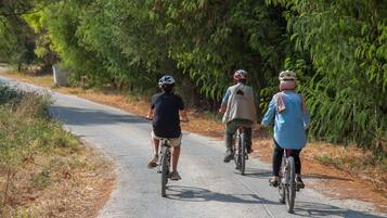 Drie fietsers op een verhard pad, omgeven door groen.