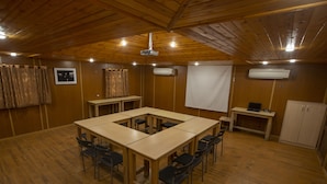 A conference room with a large table, chairs, a projector, and an air conditioning unit.