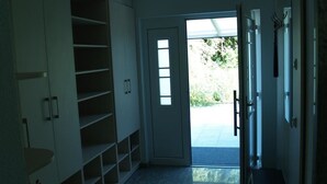 Ein Flur mit einer eingebauten Schrankwand, einer Tür, die nach draußen führt, und einem kleinen Tisch mit einem Stuhl.
