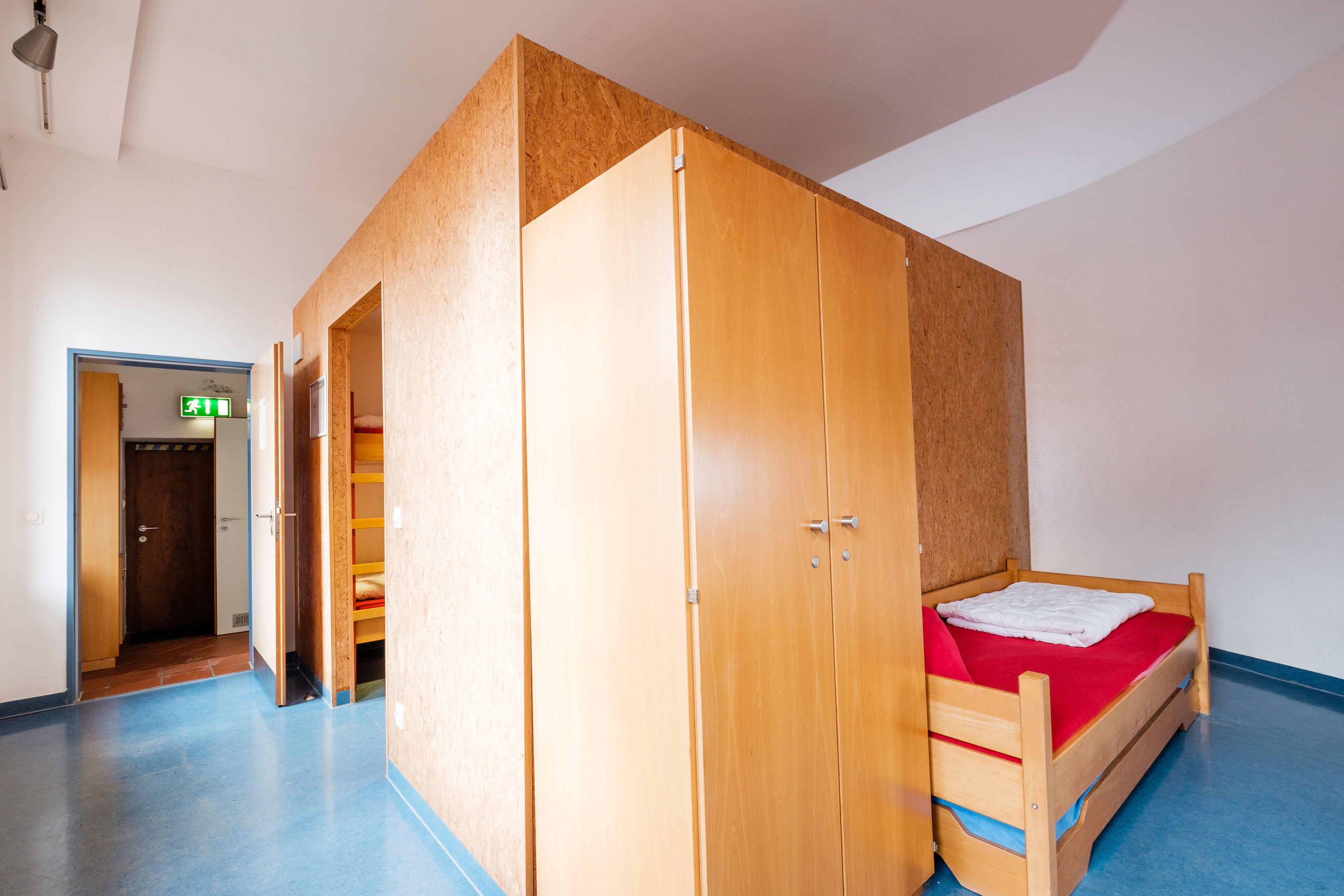 Una habitación con literas, un armario y una puerta que da a otra estancia.