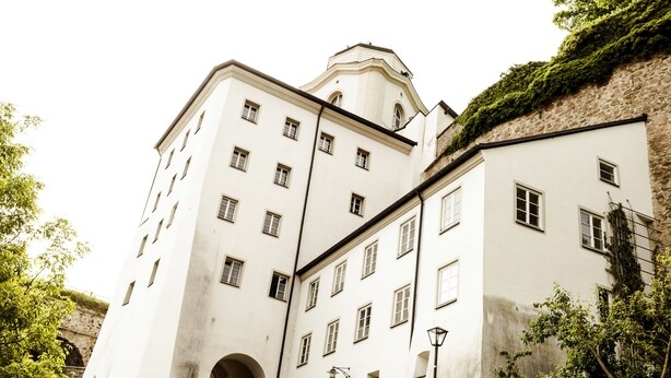 Un edificio a più piani con facciata simmetrica, numerose finestre e un ingresso centrale ad arco.