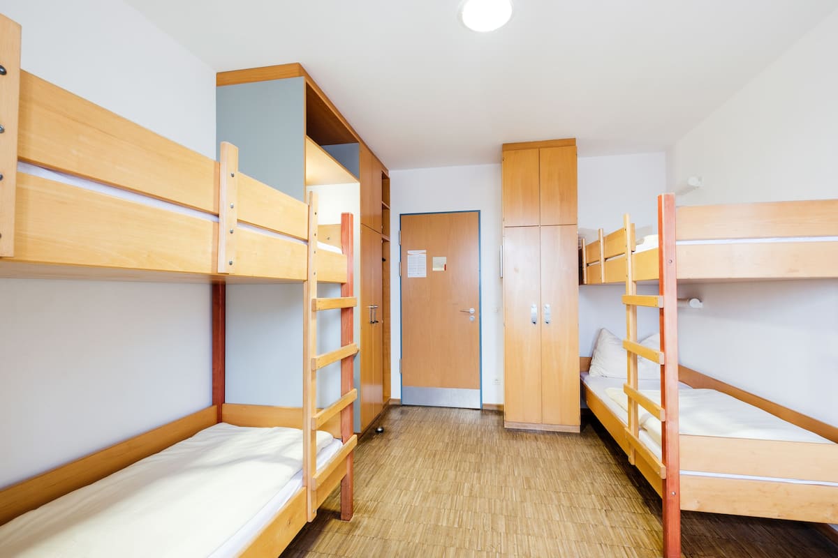 A room with bunk beds, wooden cabinets, and a door.
