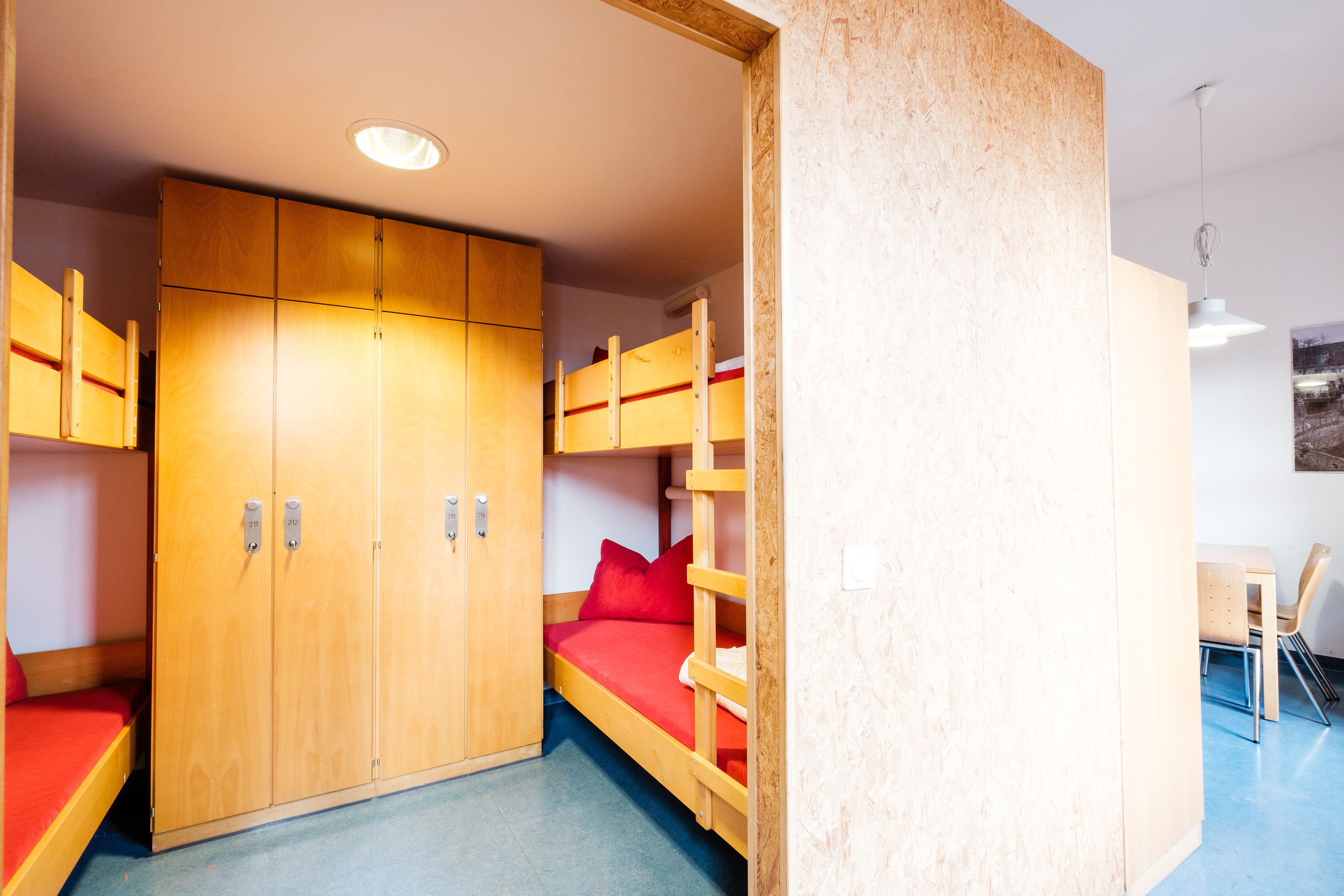 Una habitación con literas, un armario y un escritorio con sillas.