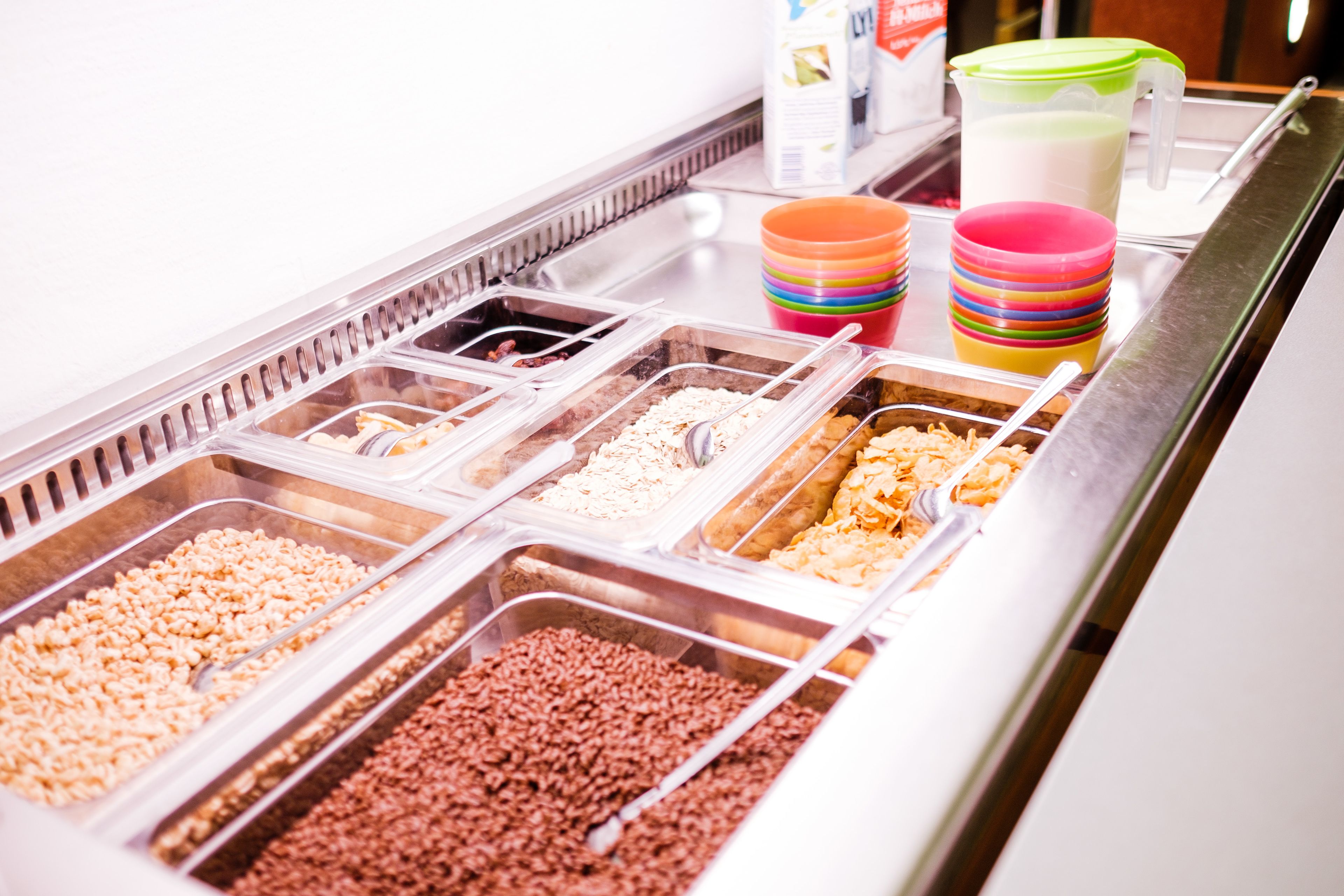 A buffet with various food items in clear containers, including rice, beans, and other grains.