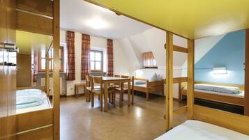 Ein Zimmer mit Etagenbetten, einem Holztisch und einem Schreibtisch.