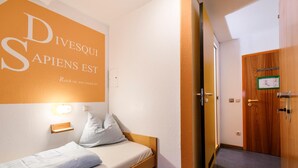 Ein Hotelzimmer mit einem Bett, einer Wandleuchte und einer Tür mit Holzpaneel.