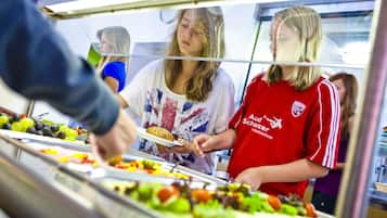Ein reichhaltiges Buffet mit verschiedenen Speisen und einer Person, die das Servieren übernimmt.