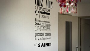 A wall with motivational French text and a decorative chandelier. - Chambre d'hôtes Agnes et Olivier (Burlats)