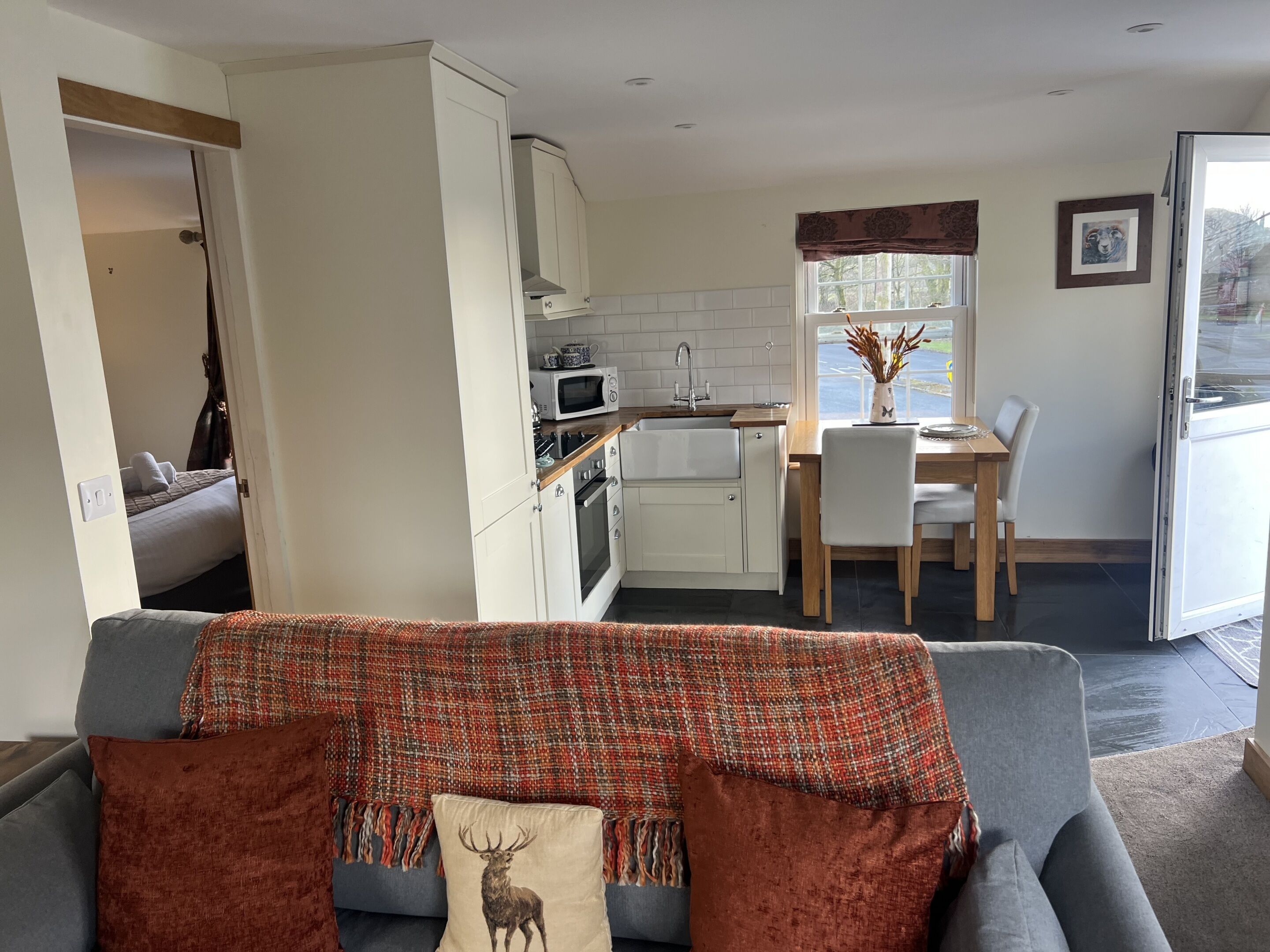 A compact living space with a kitchenette, a dining area, and a sofa with decorative pillows.