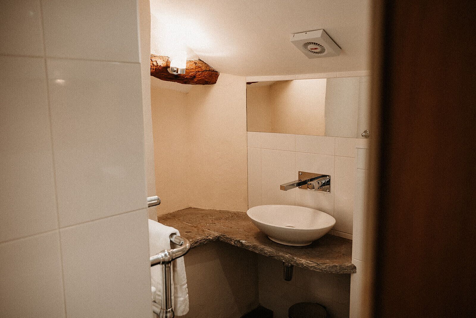 Un baño con lavamanos blanco, un espejo y un toallero.