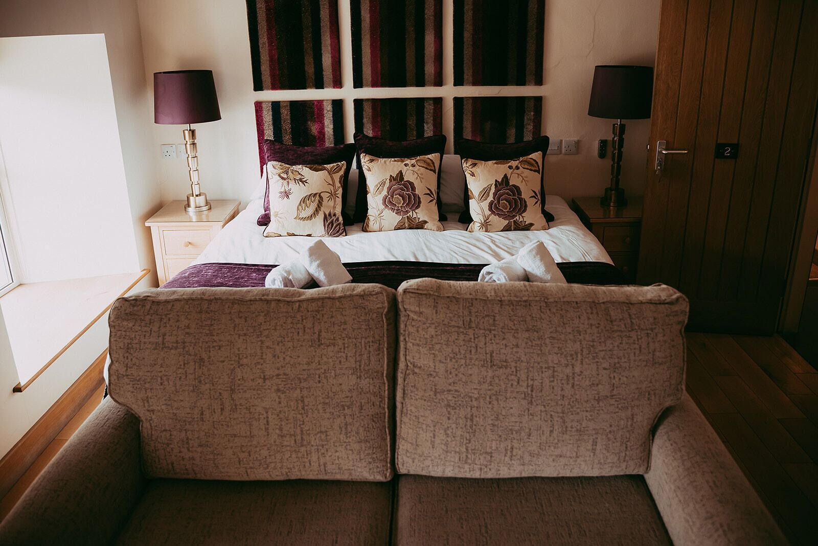 A hotel room with a bed, two bedside lamps, a nightstand, a window, and two armchairs.