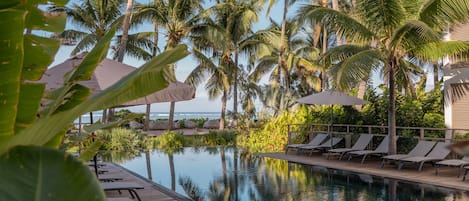 Una piscina al aire libre, sombrillas, sillones reclinables de piscina