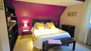 Ein Schlafzimmer mit einem Bett, Nachttischen, einer Bank und einem Fenster mit Vorhängen.