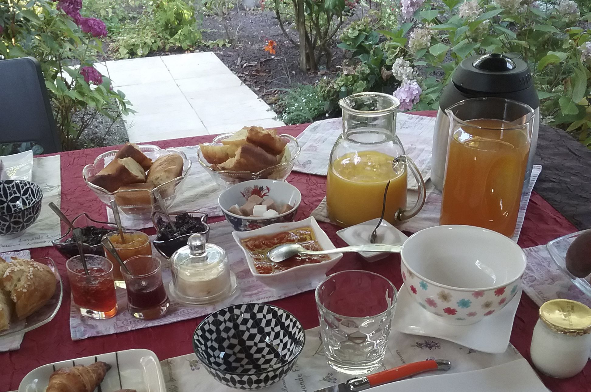 A breakfast table with various food items and drinks, including bread, pastries, and a pitcher of orange juice.