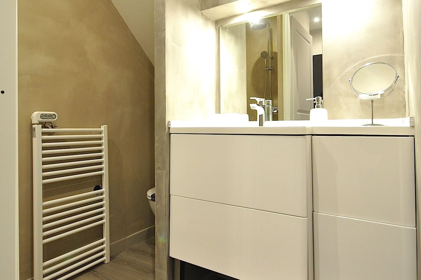 Un bagno con un portasciugamani bianco, uno specchio e un lavandino.
