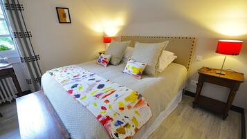 A neatly made bed with a colorful blanket, two bedside lamps, and a wooden nightstand.