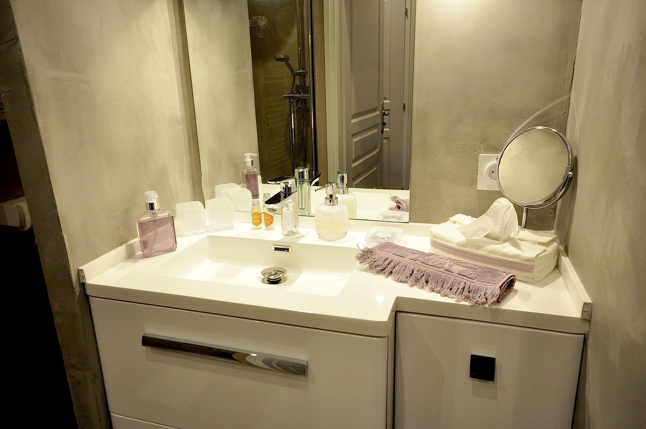 Un baño moderno con un lavamanos blanco, un espejo grande y una zona de ducha.