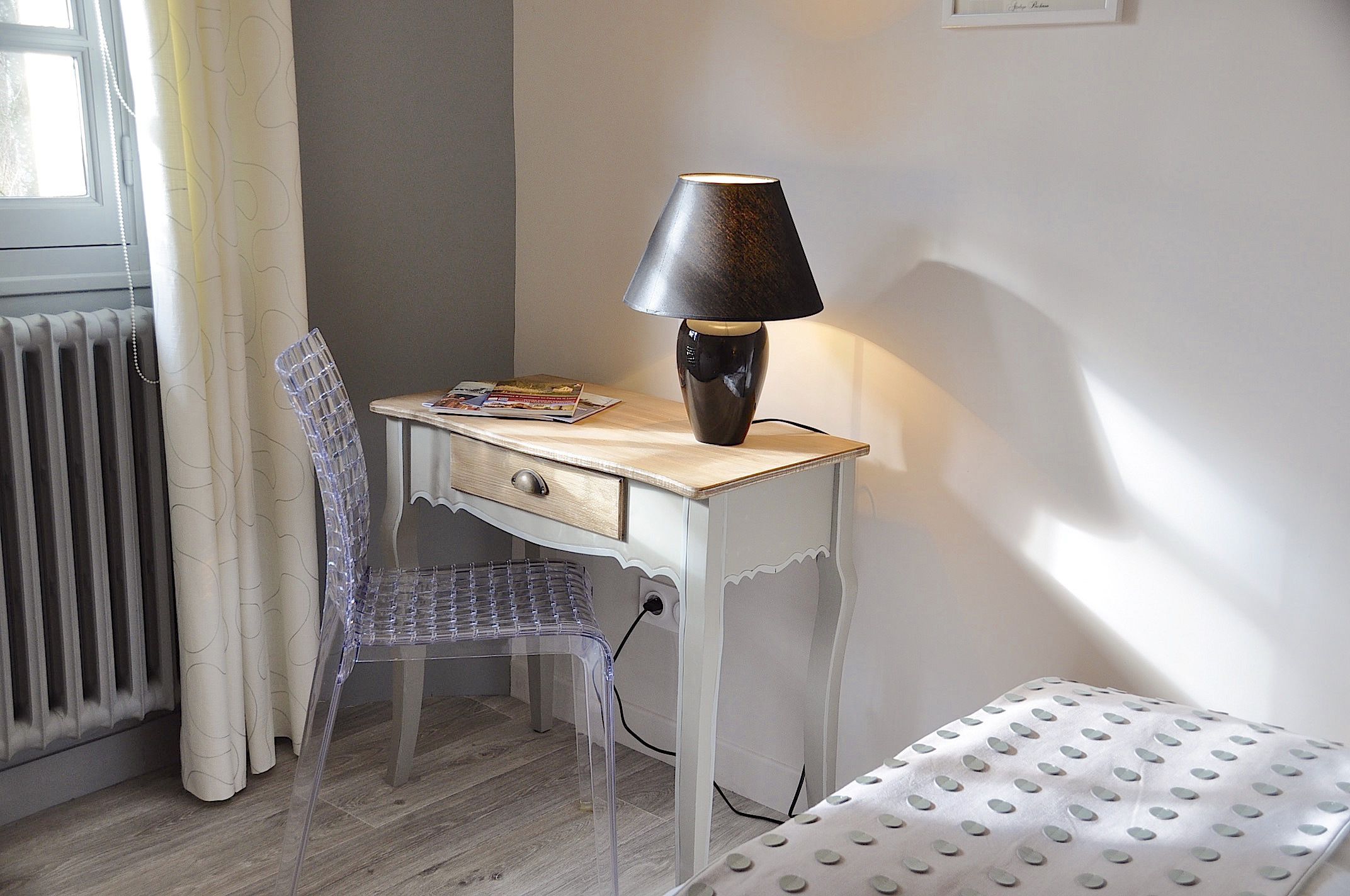 A small, neatly organized room with a desk, chair, and a lamp.