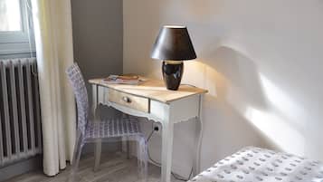 A small, neatly organized room with a desk, chair, and a lamp.