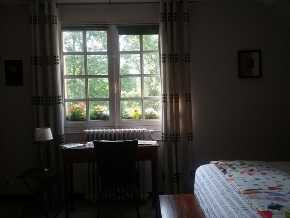 Una habitación con cama, escritorio y ventana con cortinas.