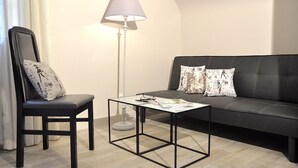 A modern living room with a black leather sofa, a matching armchair, and a small coffee table. - Au Jardin de Lisa (Cherré-Au)