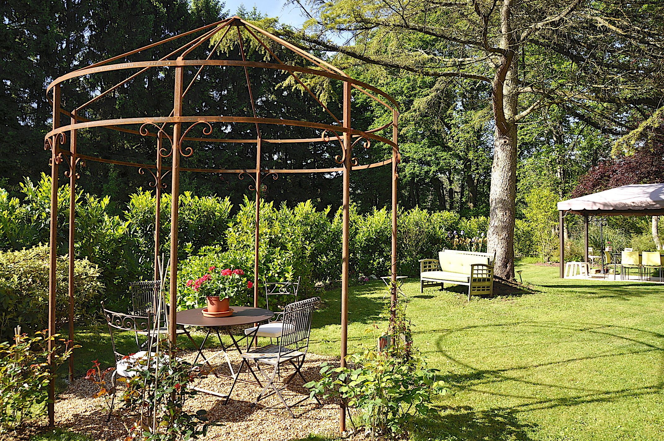 Un belvédère avec une table et des chaises, situé dans un jardin.