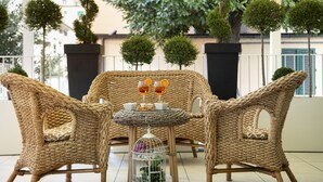 Wicker furniture with a table and chairs, a small birdcage, and potted plants. - Hotel Ariston & Spa (Montecatini Terme)