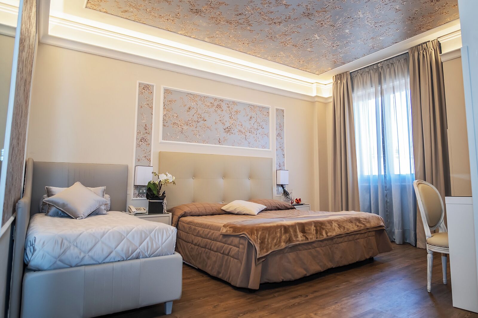 A hotel room with two beds, a desk, and a chair.