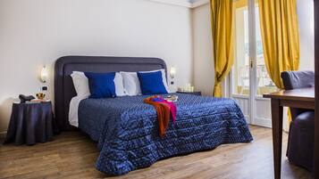 Una camera da letto con un letto grande, un comodino con una lampada, una sedia e vista all'esterno attraverso una finestra con tende gialle.