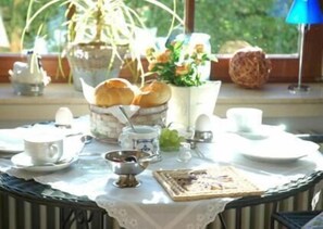 A breakfast table set with bread, eggs, and a cup, with a view of greenery outside. - Gästehaus Tepel (Winterberg)