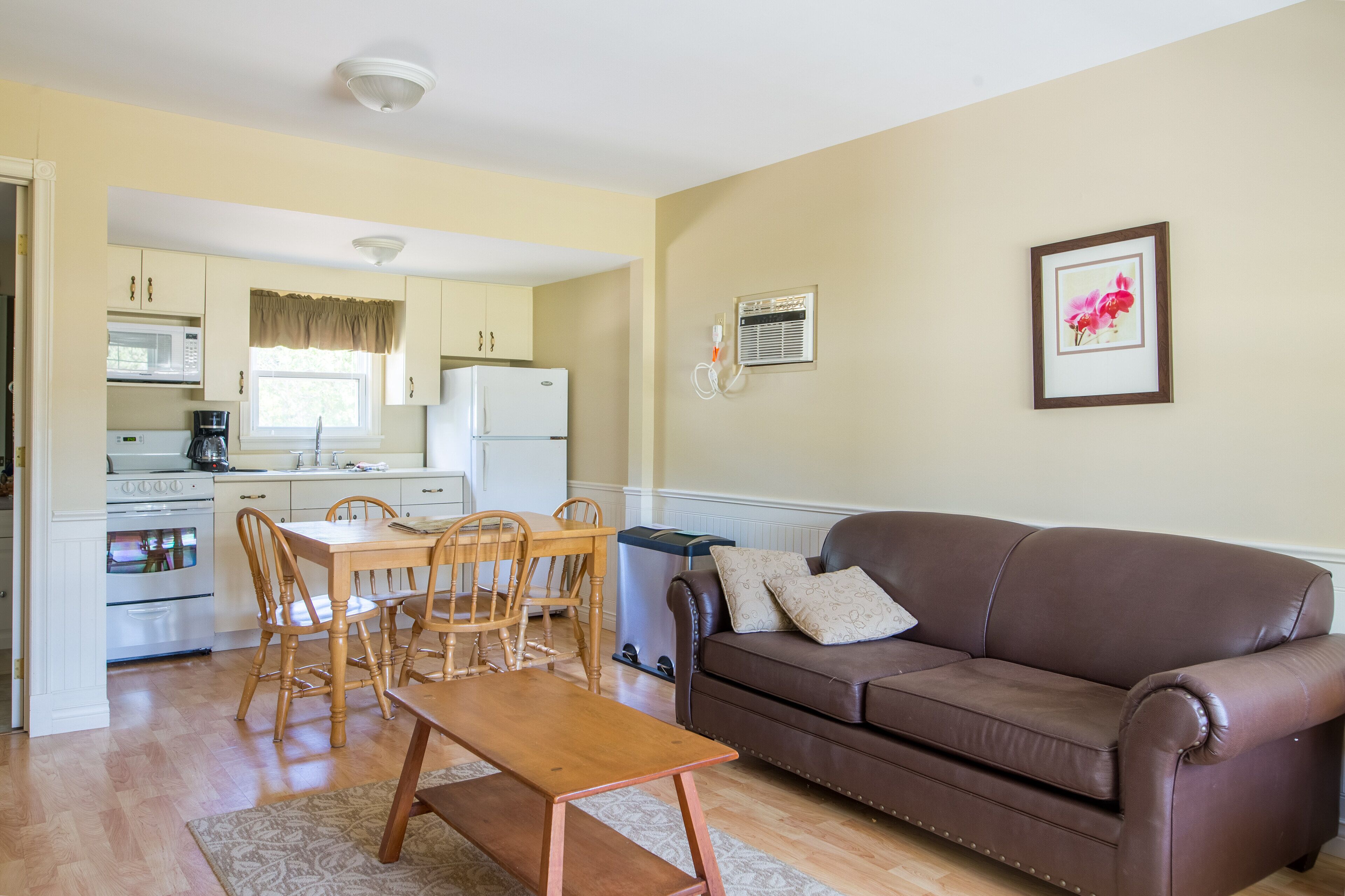 A compact living space with a kitchenette, a dining area, and a seating area with a couch and a table.