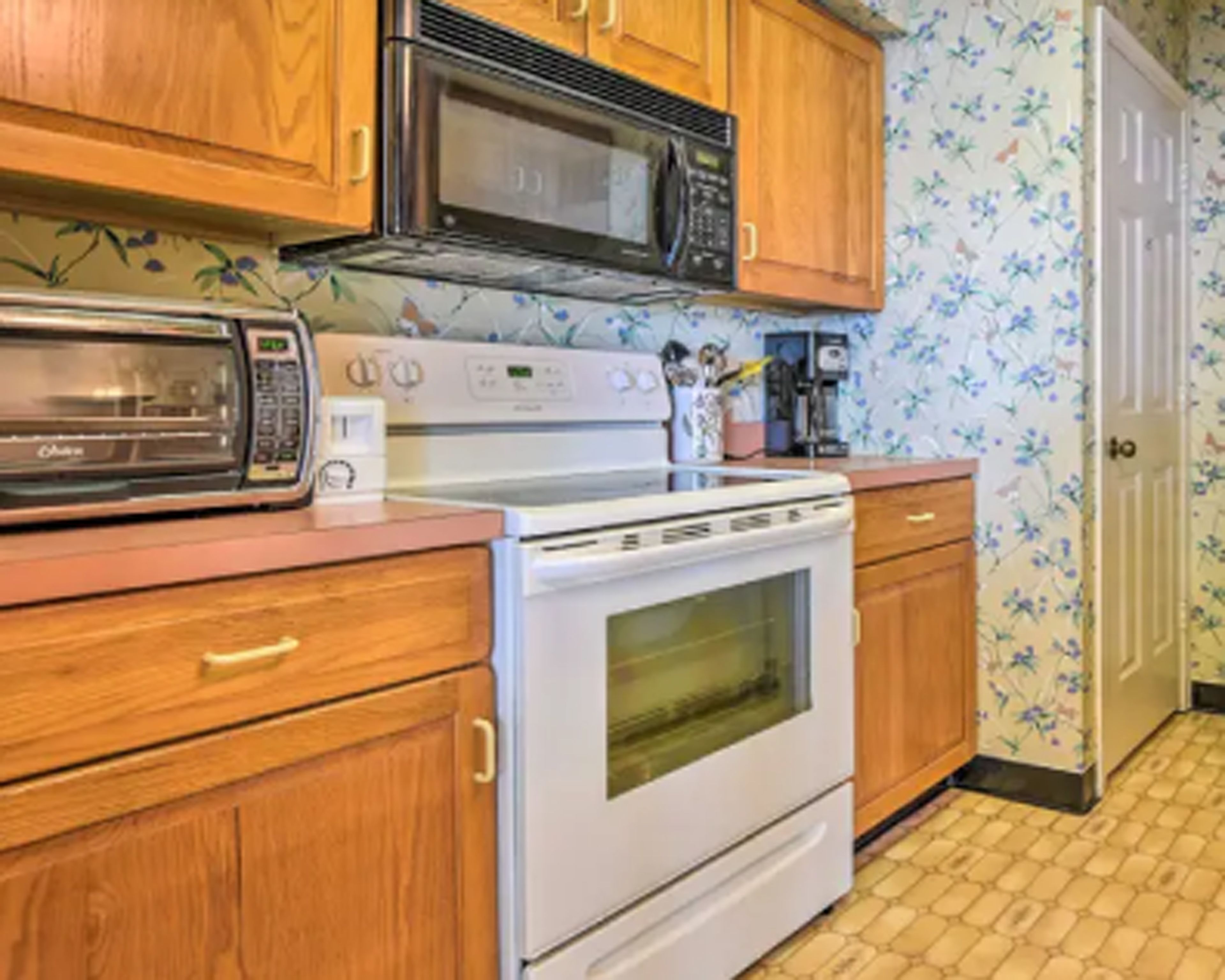 A kitchen with wooden cabinets, a microwave, a toaster, and a stove.